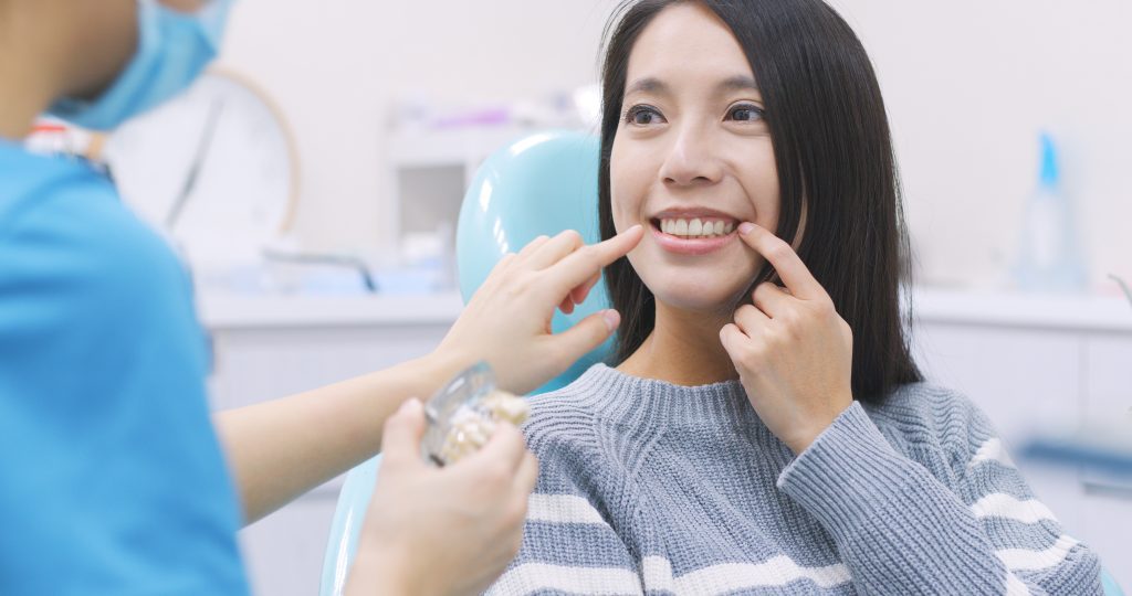 A dentist examining a woman who is smiling.