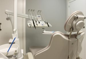 Empty dental treatment room with chair and overhead instrument tray