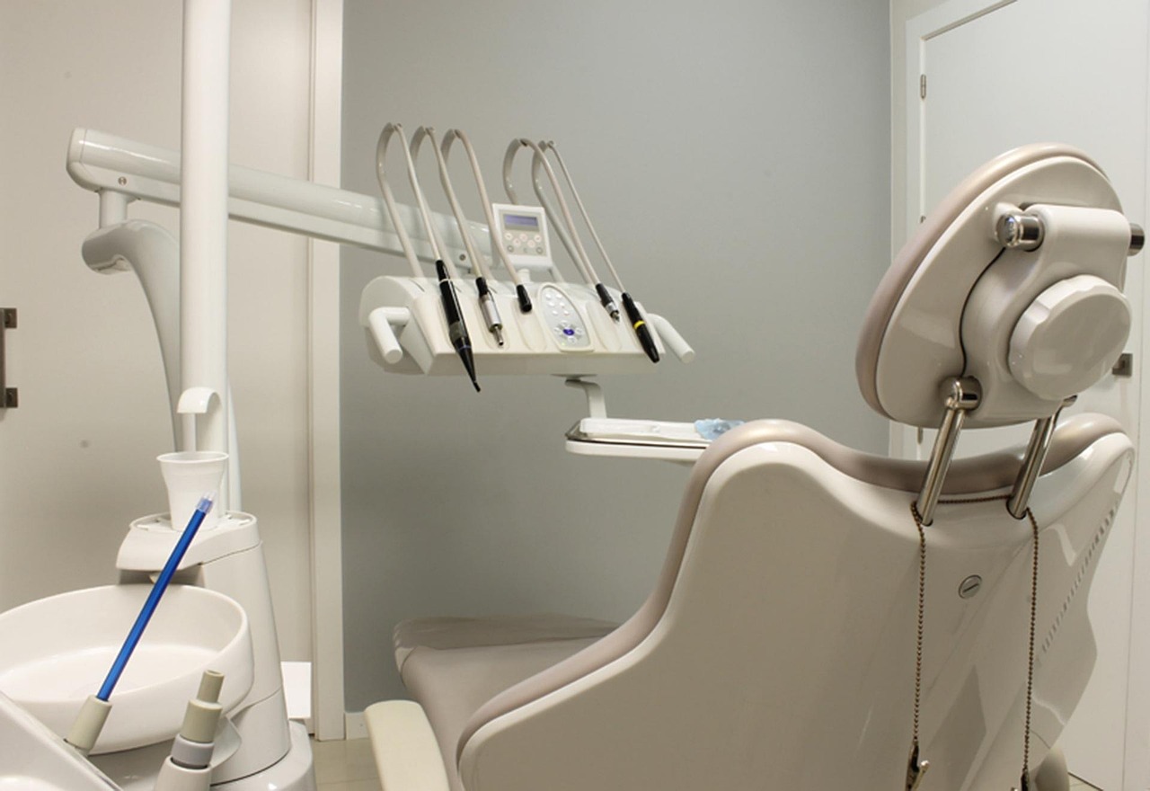 Empty dental treatment room with chair and overhead instrument tray